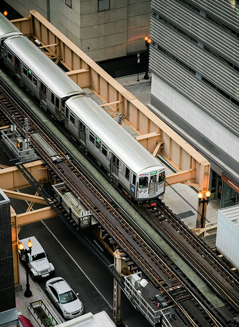 A train is traveling down the tracks near some buildings.