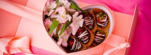 A box of strawberries and cookies with flowers.