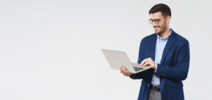 A man in glasses is holding a laptop