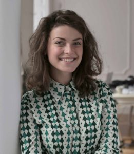 A woman in green and white shirt smiling for the camera.